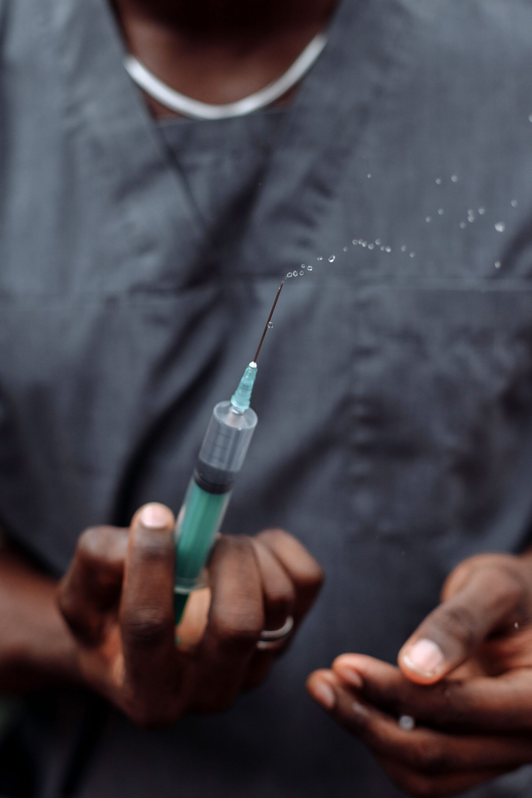 A medical professional in a gray scrub prepares a syringe with precision, highlighting healthcare expertise.