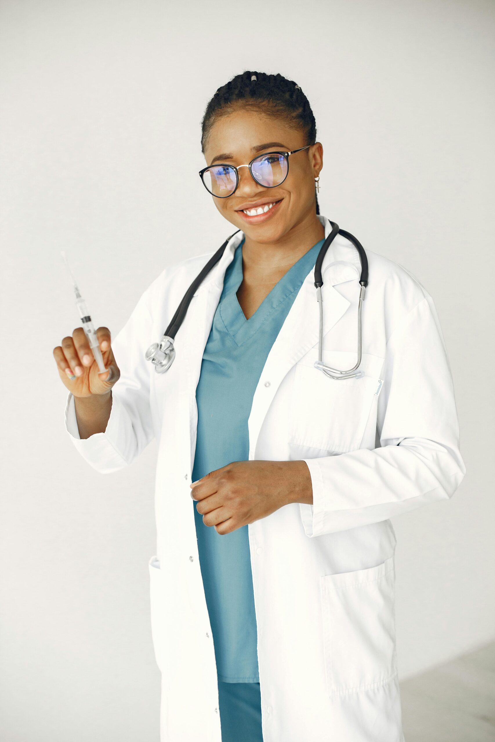 Portrait of a cheerful female doctor in a lab coat holding a syringe.
